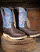 Pair of brown cowboy boots with blue and pink stitched tops on a wooden block.
