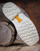 Close-up of a white Ariat shoe sole with a brand logo on a wooden surface