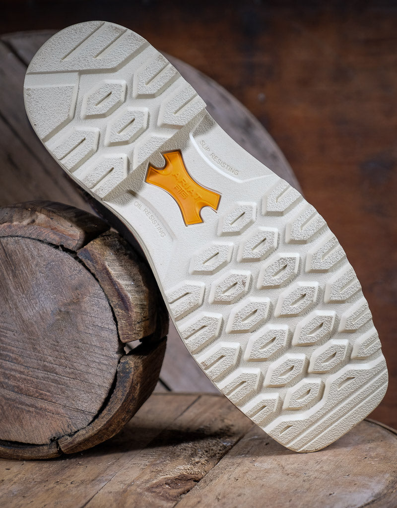Close-up of a white Ariat shoe sole with a brand logo on a wooden surface
