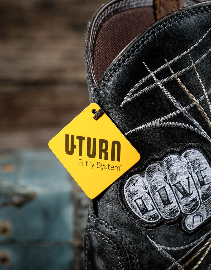 Black boot with a yellow 'U Turn' tag and 'Live' fist patch on a blurred background