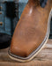 Square toe brown leather boot with stitching detail on a wooden surface
