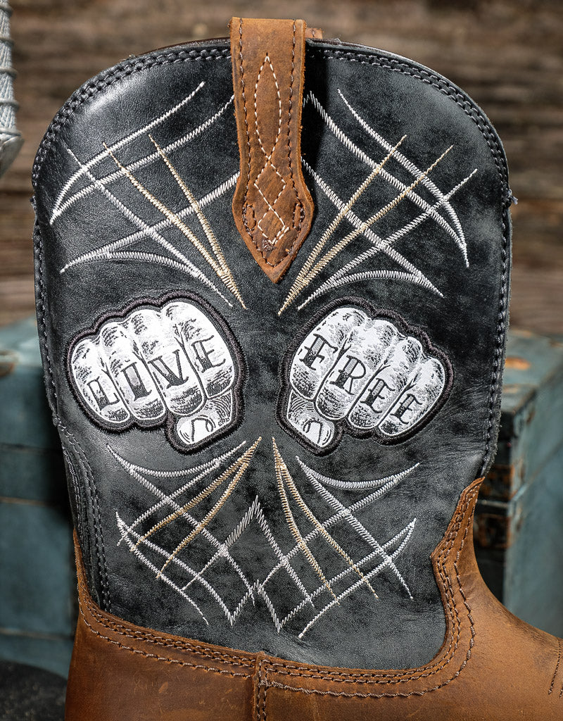 Close-up of a boot with 'Live Free' embroidery on a wooden background