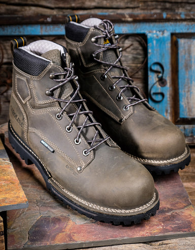 Pair of grey hiking boots on a rustic wooden surface with a blue wooden panel in the background.