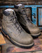 Pair of grey hiking boots on a rustic wooden surface with a blue wooden panel in the background.