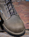 Grey leather boot with laces on a rustic wooden surface