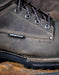 Close-up of a grey leather boot with 'Waterproof' label on a rustic surface