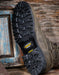 Close-up of a grey leather boot with a rugged sole on a wooden background