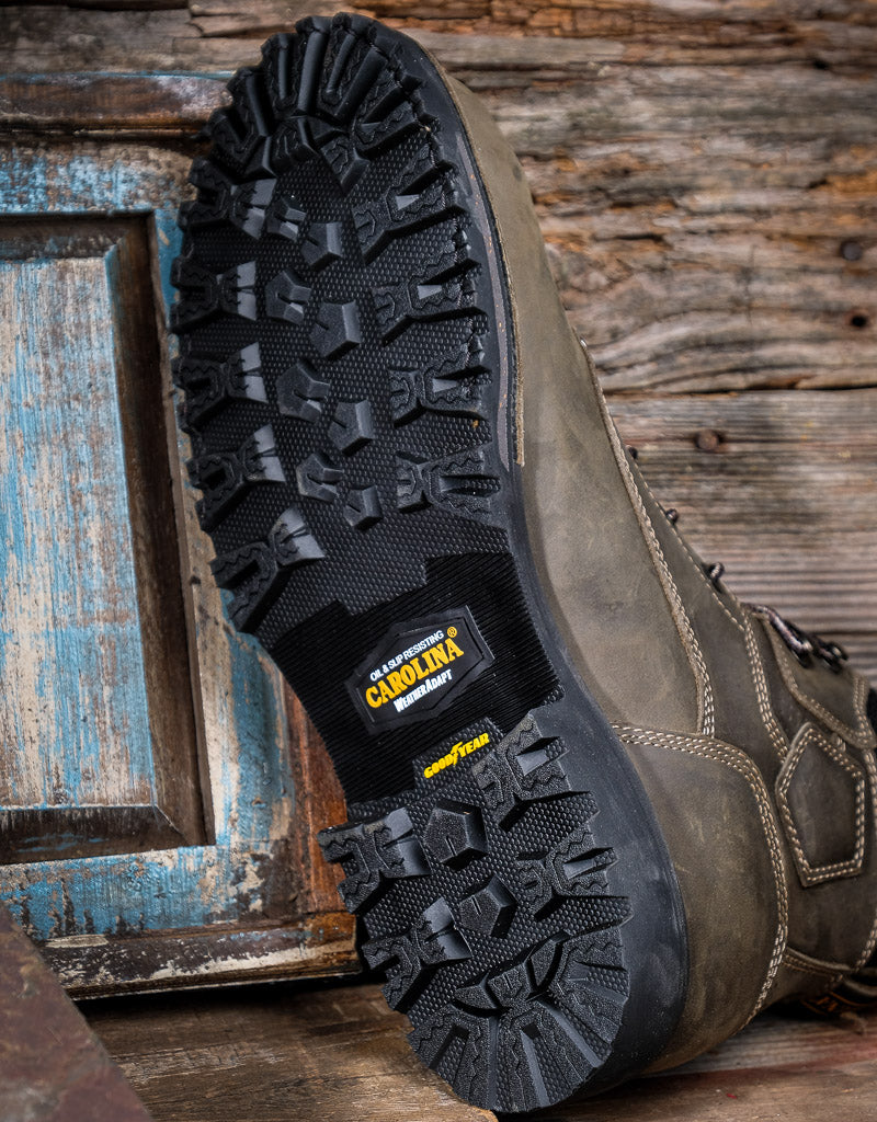 Close-up of a grey leather boot with a rugged sole on a wooden background