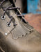 Close-up of a grey leather boot with detailed stitching and laces.