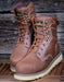 Pair of brown leather boots with visible Carolina brand logo on a wooden background