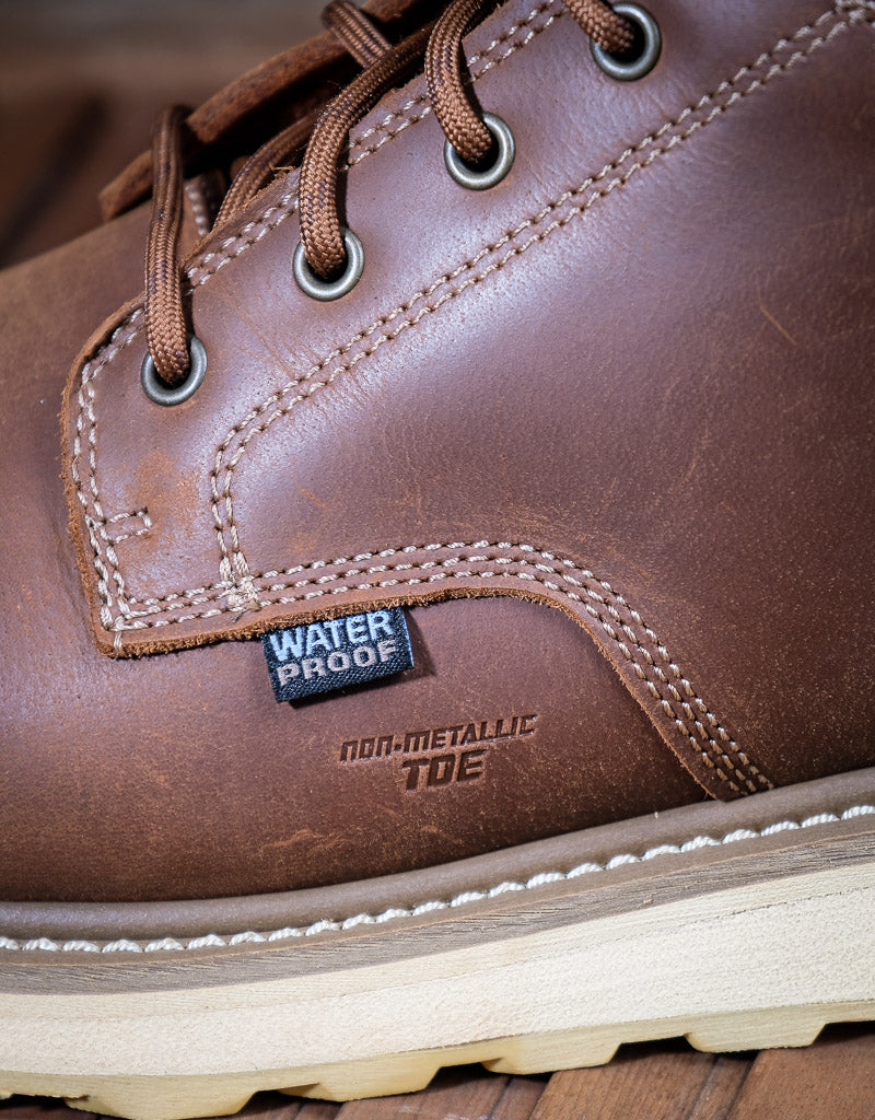 Brown leather boot with waterproof label and "Non-metallic Toe" imprinted on the leather on a wooden surface