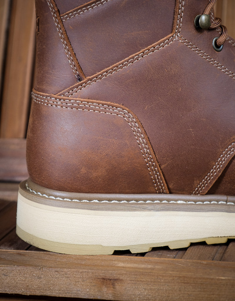 Close-up of a brown leather boot with white sole on a wooden surface