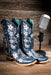Blue cowgirl boots with star patterns on a wooden surface with a vintage microphone.