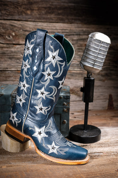 Blue cowgirl boot with star patterns on a wooden surface with a microphone in the background.