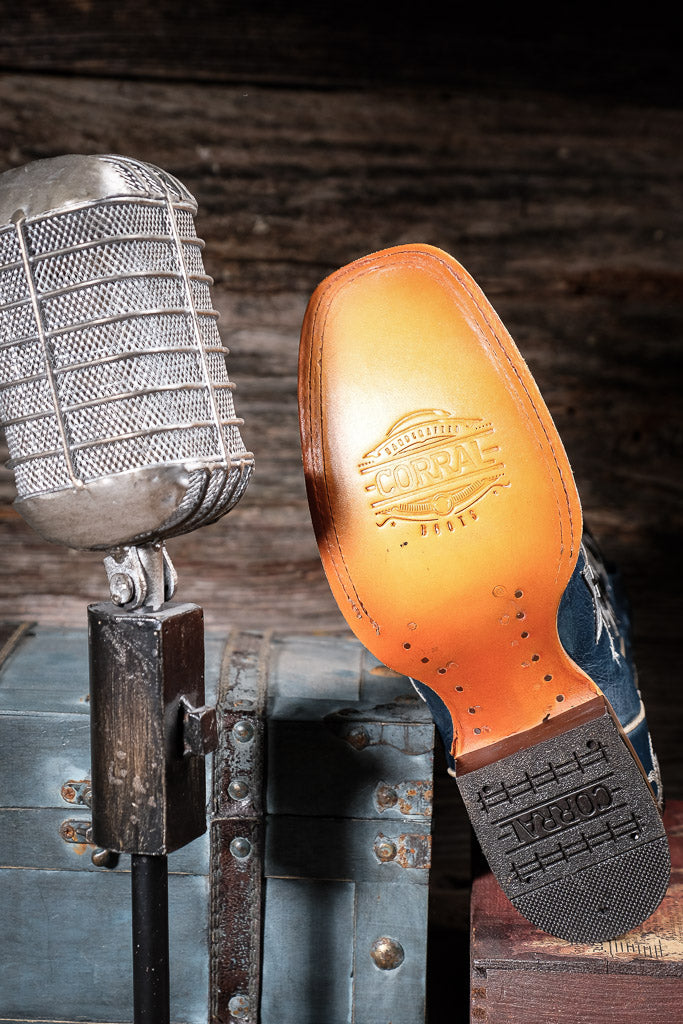 Shoe sole with a Corral brand logo next to a vintage microphone on a wooden background