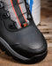 Close-up of a black and gray DC hiking boot with orange accents, resting on a rustic wooden surface.