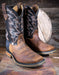Pair of brown and black cowboy boots on a wooden surface with a rustic background.