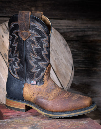 Brown and black cowboy boot with intricate western design on a wooden background