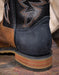 Close-up of a black leather boot heel with brown stacked heel base on a wooden surface
