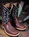 Pair of brown and dark blue cowboy boots with western stitching on a rustic wooden surface.
