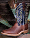 Brown and blue cowboy boot with intricate western stitching on a rustic wooden background
