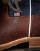 Close-up of a brown leather boot with an American flag label on a dark background