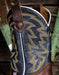 Close-up of a cowboy boot with intricate western stitching and leather details on a rustic background.