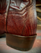 Close-up of a brown leather boot with lizard leather textured scales on the heel