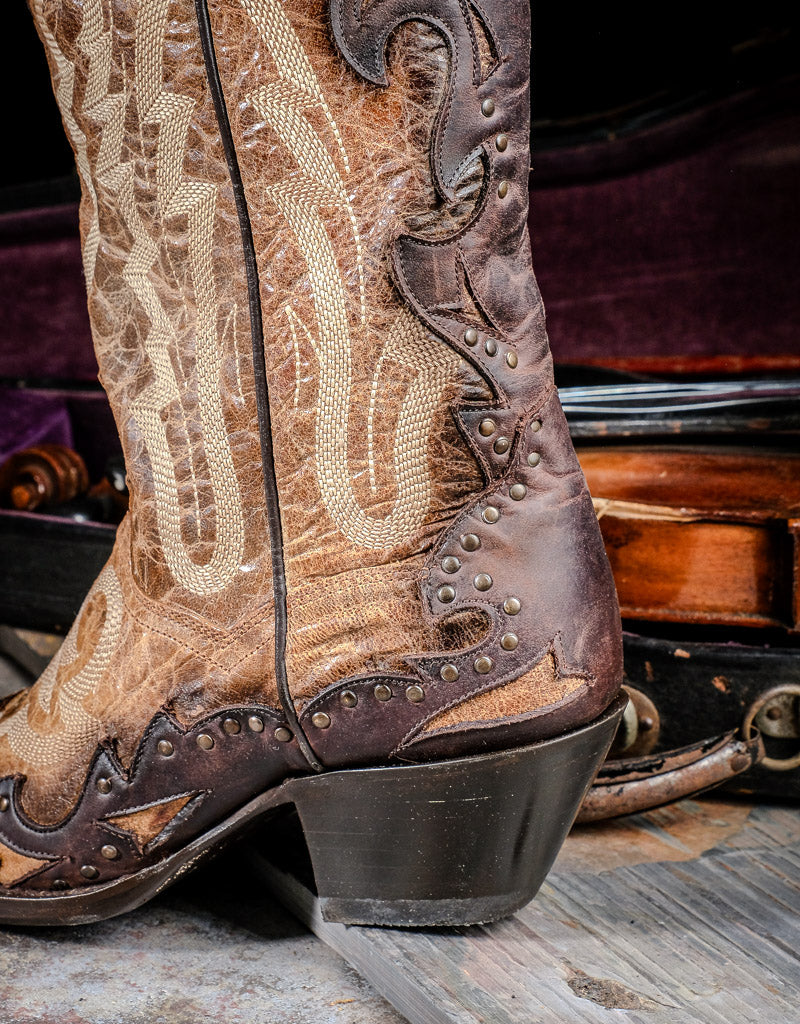 closeup of cowboy heel, top of the boot is tan with brown leather overlay inching up the back of the boot