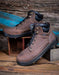Brown leather boots with black soles on a wooden surface