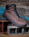 Brown leather boot with black sole on a wooden surface