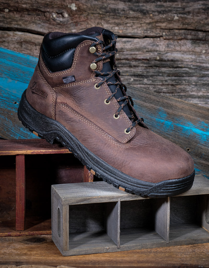 Brown leather boot with black sole on a wooden surface