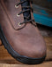 Brown leather boot with black sole on a wooden surface