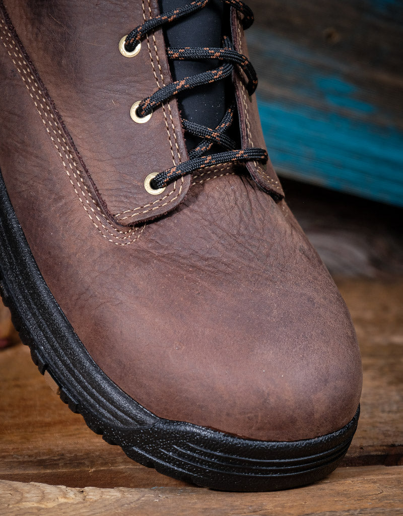 Brown leather boot with black sole on a wooden surface