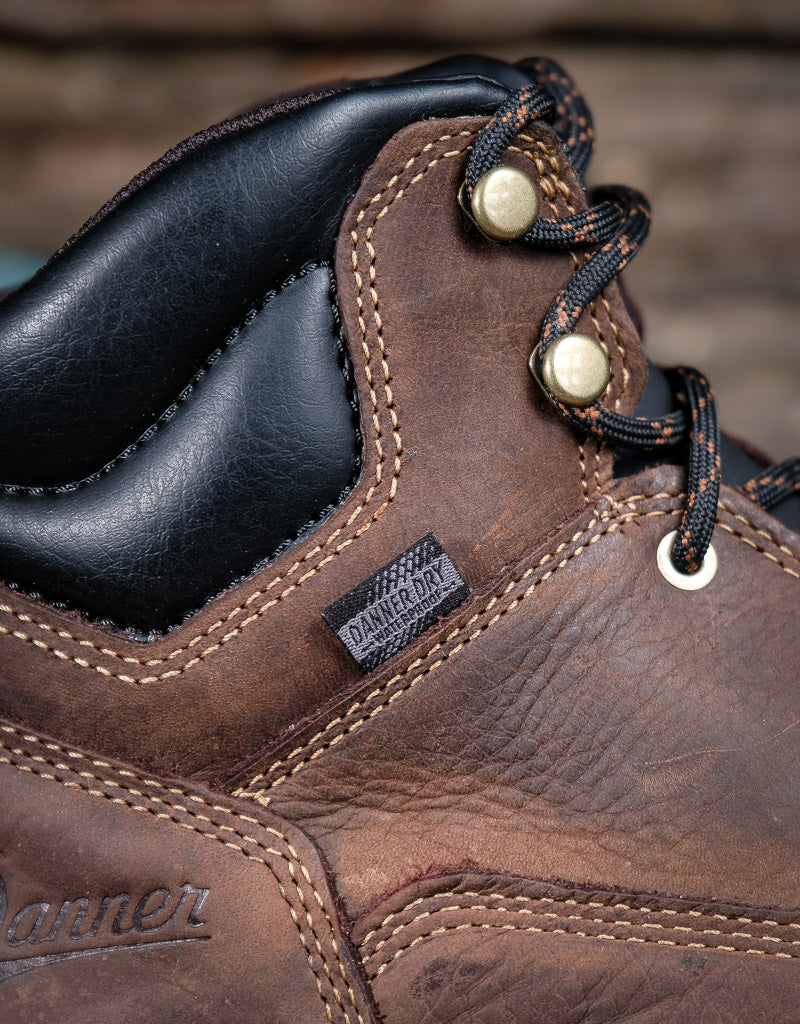 Close-up of a brown leather boot with laces and a label saying Danner Dry waterproof on a blurred background