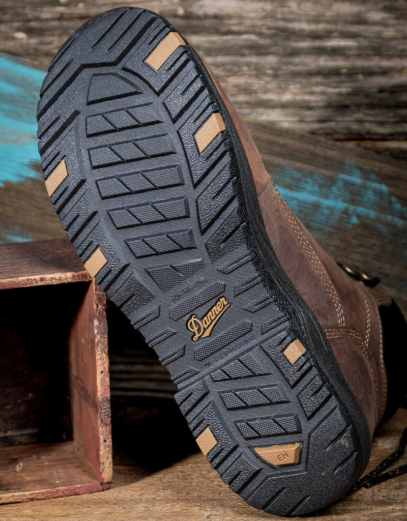 Brown boot with a detailed tread pattern on a wooden surface