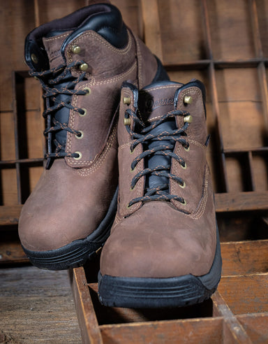 Pair of brown leather boots with black soles on a wooden background