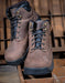 Pair of brown leather boots with black soles on a wooden background