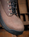 Brown leather boot with black sole on a wooden surface