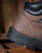 Brown leather boot with black sole on a wooden surface