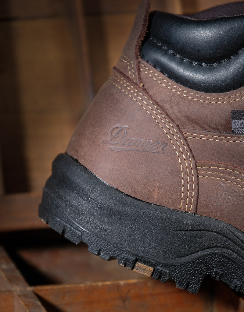 Brown leather boot with black sole on a wooden surface
