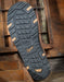 Close-up of a shoe sole with tread pattern and Danner brand logo on a wooden background