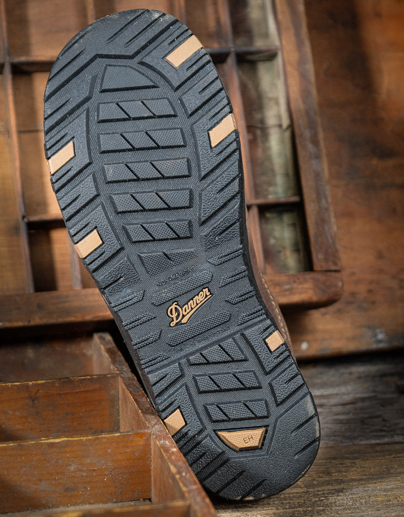 Close-up of a shoe sole with tread pattern and Danner brand logo on a wooden background