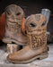 Two brown western boots with skulls imprinted on the tops