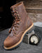 profile of 8" laceup brown boot with the heel propped up on the box