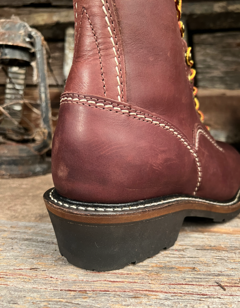 Close-up of a brown leather boot heel with visible stitching on a wooden surface.