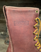 Close-up of a brown leather boot with yellow laces and Wesco branding.