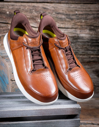 Pair of brown leather sneakers with white soles on a wooden surface