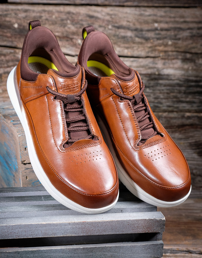 Pair of brown leather sneakers with white soles on a wooden surface