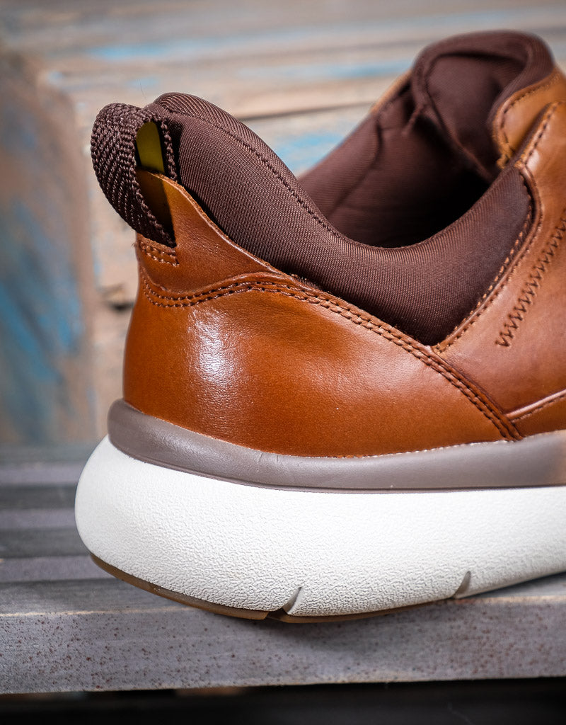 Brown leather shoe with white sole on a wooden surface
